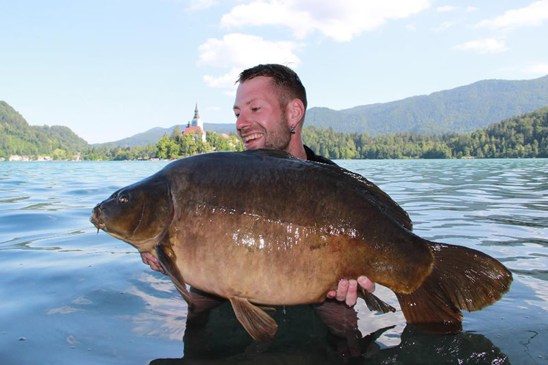Frank Schmieder Porträtbild mit einem gefangenen Karpfen in einem See in den Bergen