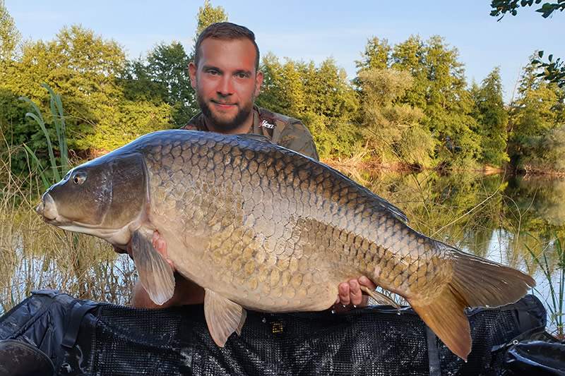 Benjamin Thomaser Porträtbild mit einem gefangenen Karpfen in einem Fluss